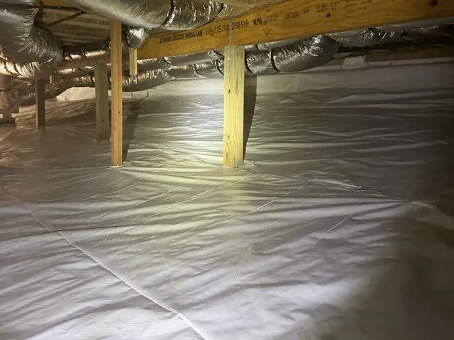 A long run of finished white crawl space liner lit by a headlamp