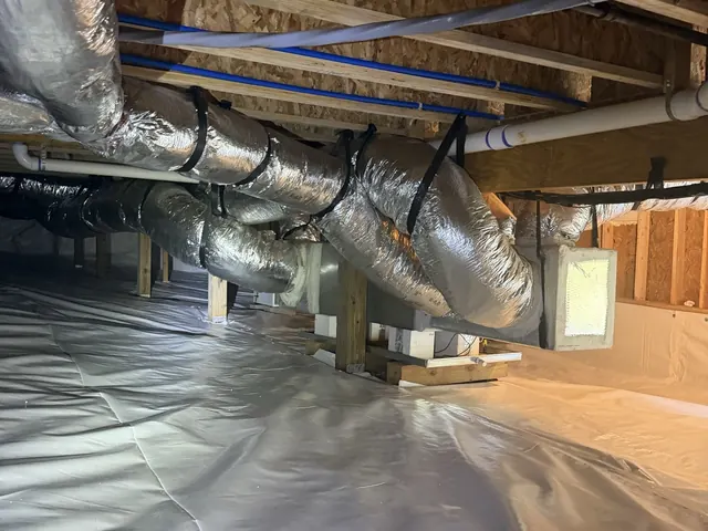 A finished crawl space: white liner on the floor under insulated ductwork