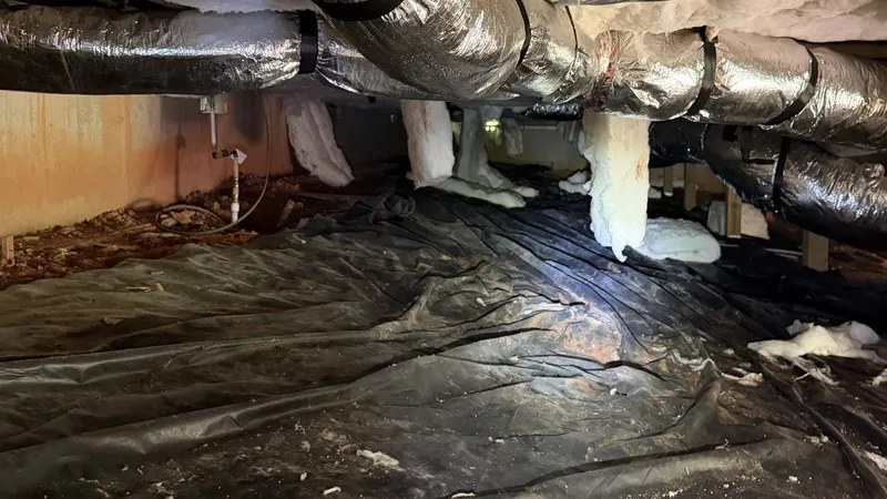 Before: ductwork over old black plastic and bare dirt in a crawl space