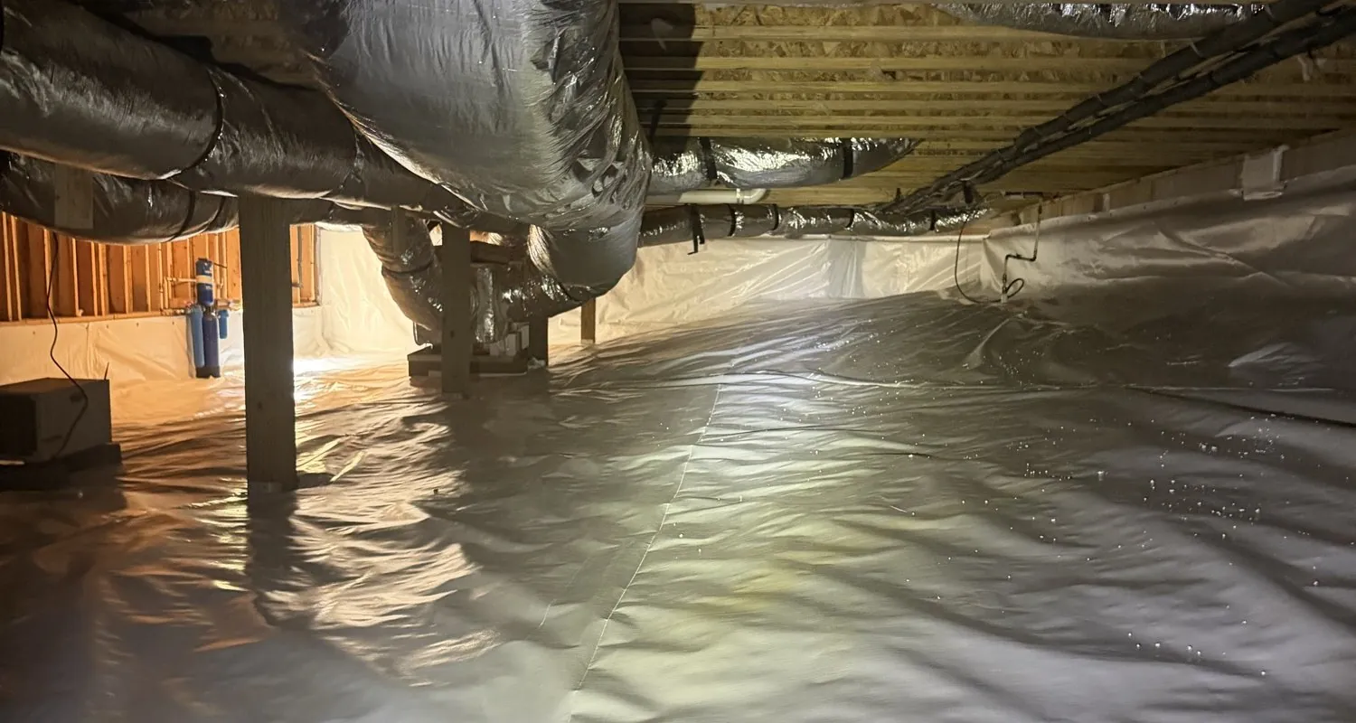 A crawl space Crawl Space Doctors sealed: white liner over the floor and up the walls, ducts and joists overhead, lit by a headlamp