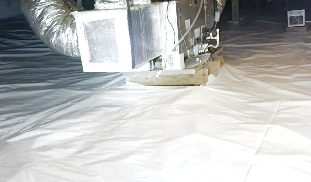 After: the same crawl space and the same air handler, the floor sealed under a white liner